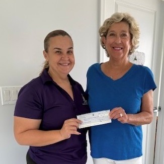 Jennifer Reynolds presenting a cheque for $1000.00 to Felisiana Ebanks for Northside Community Development Fund to help support Holiday events for children in North Side. This is part of the CKPOA charity outreach.